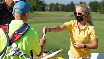 Woman handing caddy some items.