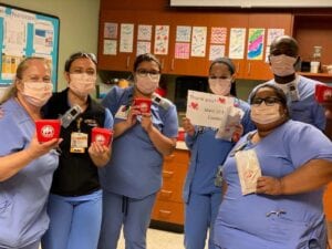 six people in scrubs and masks hold up food donated by Panda Express