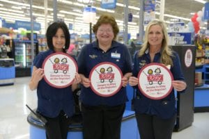Walmart associates holding Donate to Riley at the Register signs
