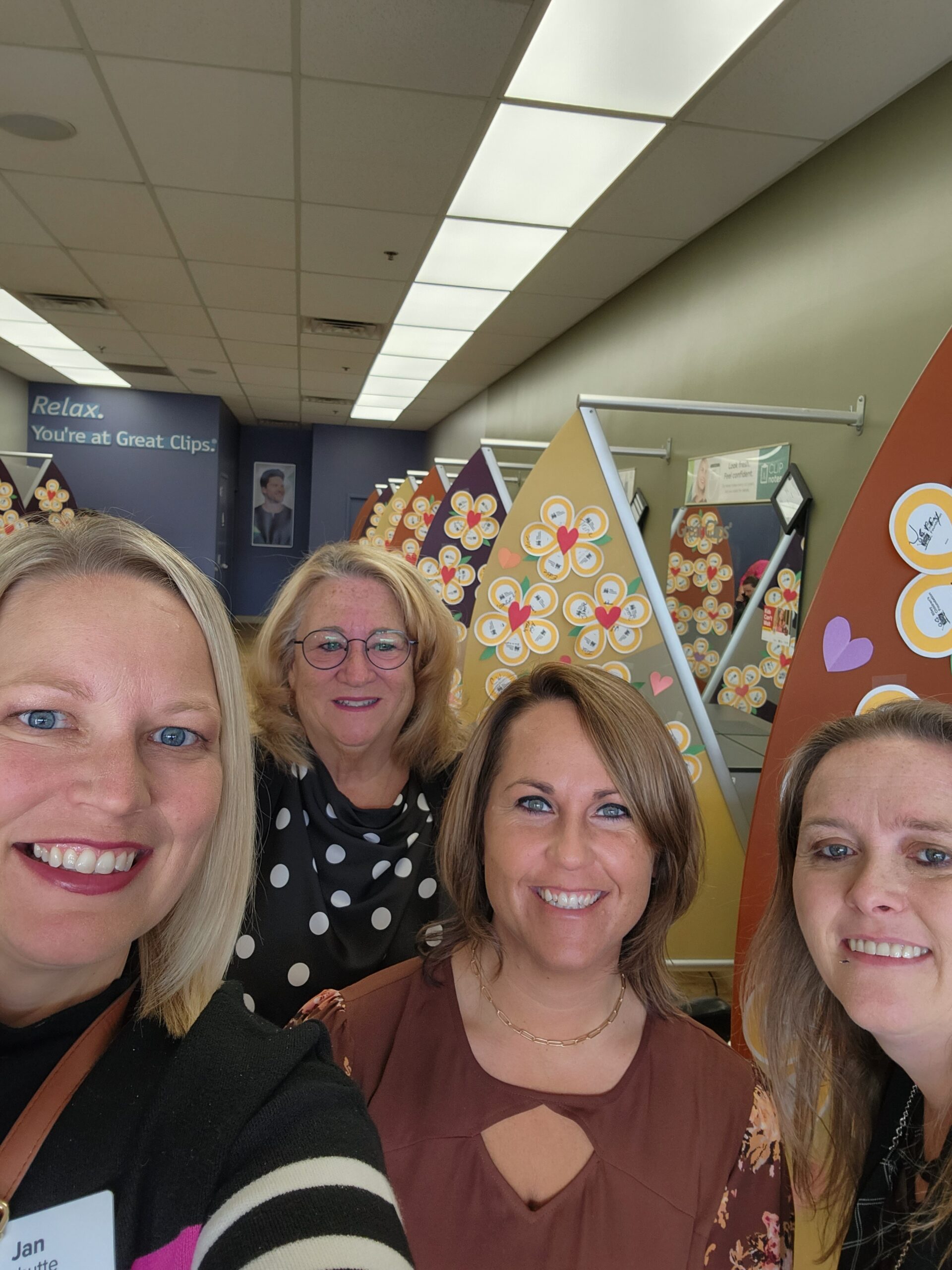 Four women take a photo in a Great Clips salon with Children's Miracle Network Balloons in the background. 