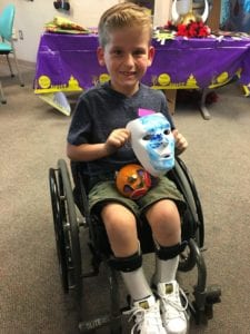 Boy in wheelchair showing off the mask he painted at the Spirit Halloween party held at UC Davis Children's Hospital. 