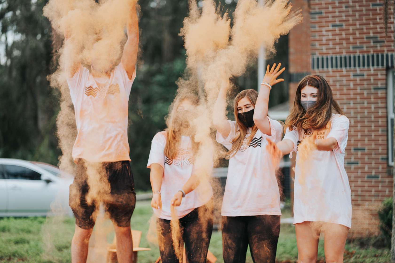 Participants throw orange powder at the Miracles in Color 5K.