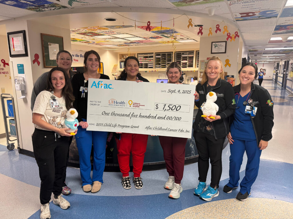 UF Health Child Life holding a check from Aflac.