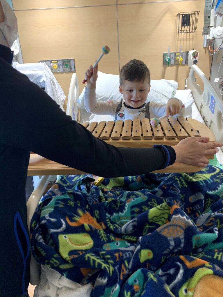 Henry playing a xylophone during music therapy