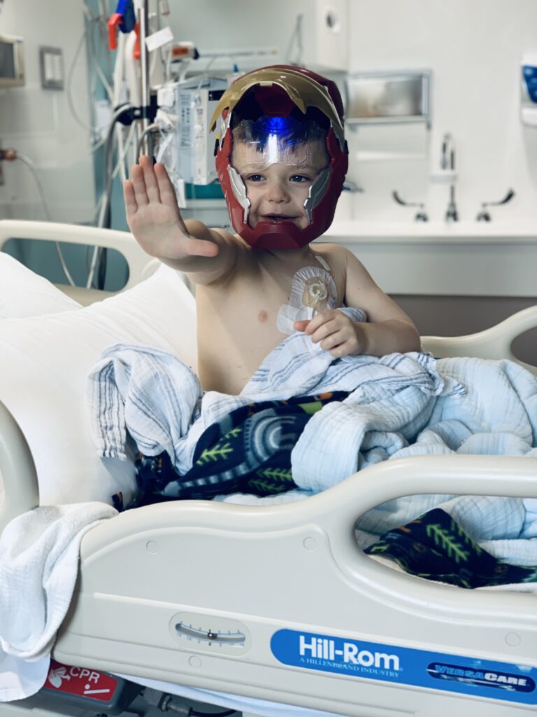 Henry posing in his hospital bed wearing an Iron Man mask