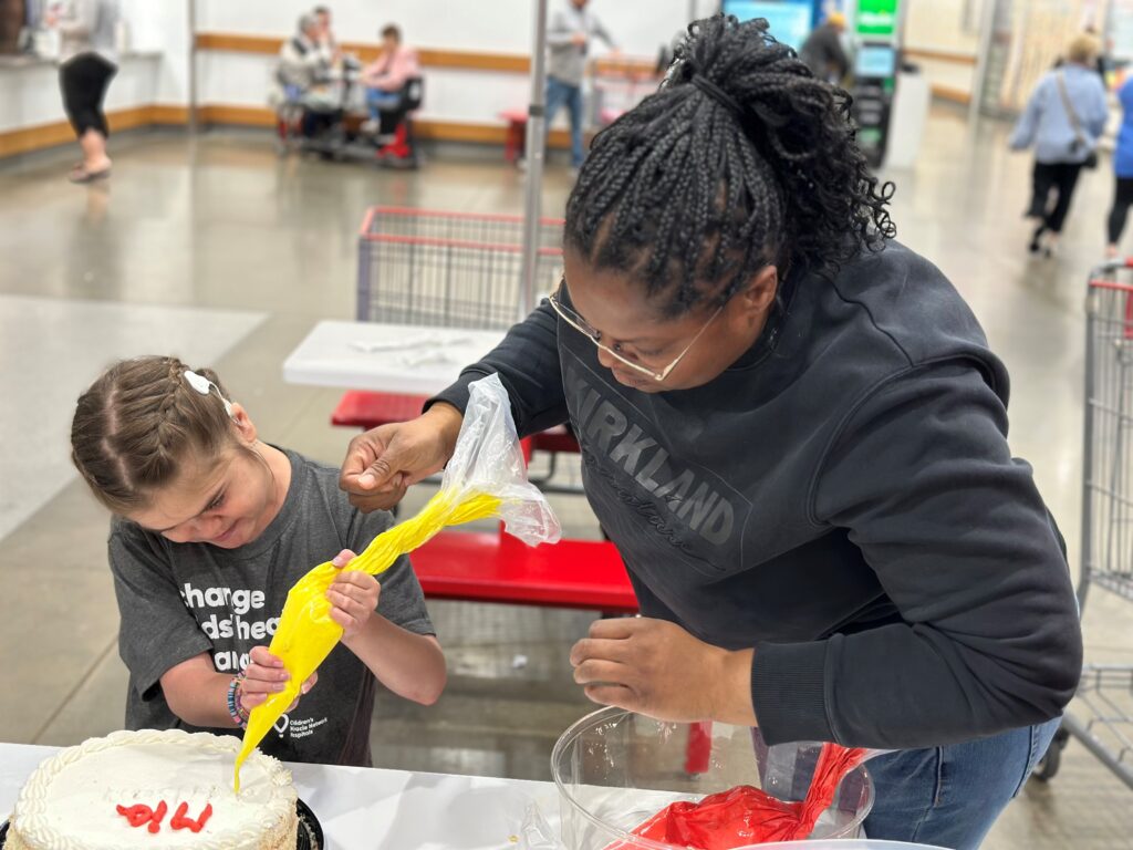 Karen, top fundraiser and incredible cake decorator, teaches Mia how to decorate!
