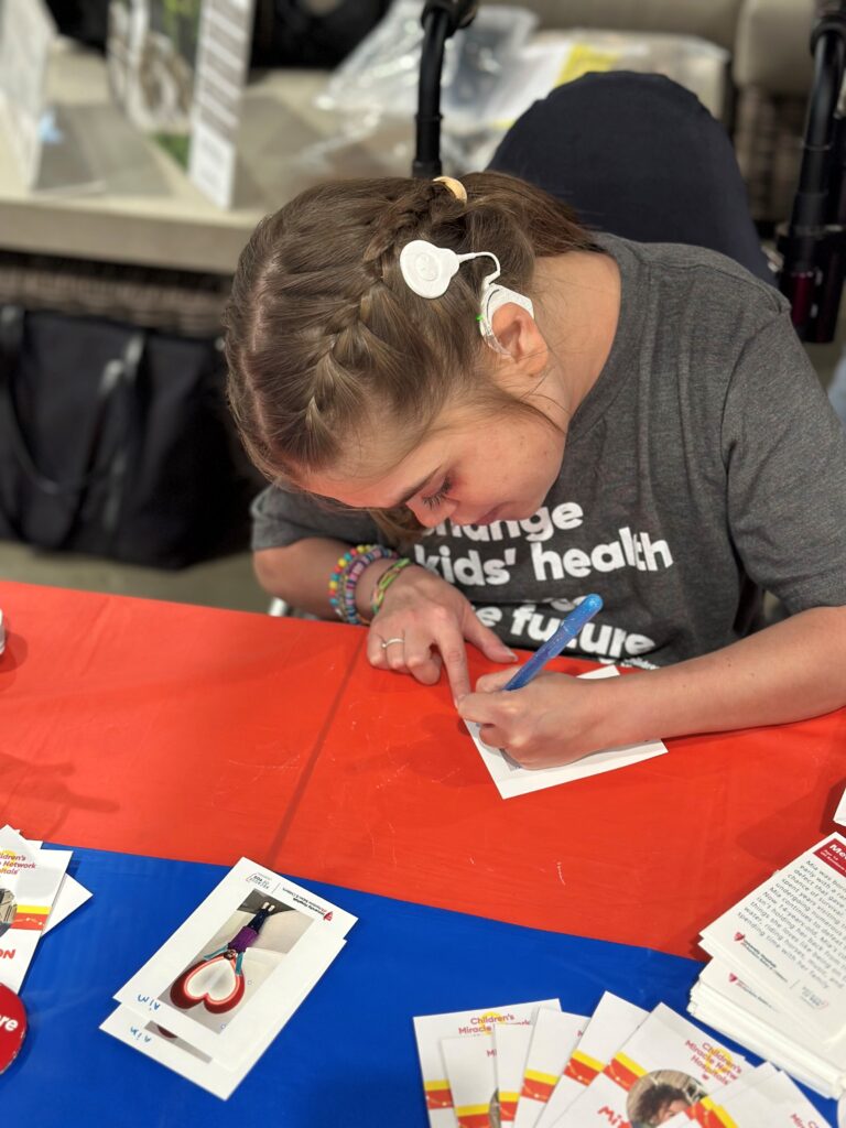Mia signs an autograph for a Costco customer
